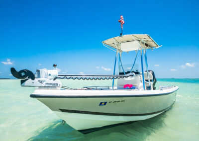 Close-up front angle of a center console boat in shallow turquoise water under a bright blue sky