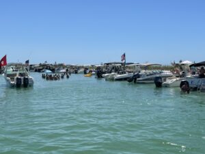 Boats rafted together at Keewaydin Island with groups of people in the water partying and floating under the Florida sun.