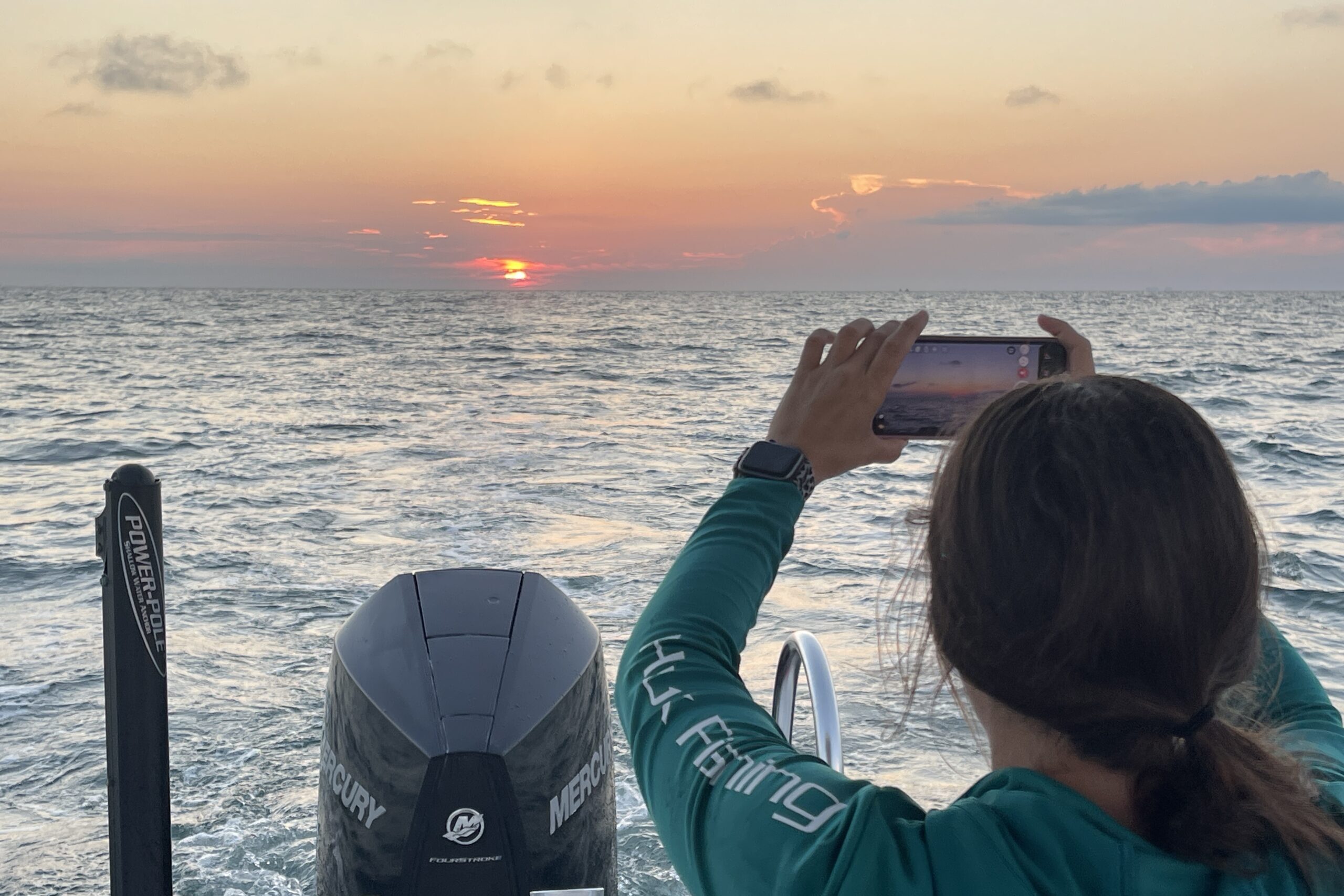 Piano Piano crew member Sam photographs a glowing sunset over the Gulf of Mexico from the back of Piano Piano.