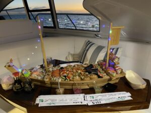 Sushi boat and gourmet setup inside a luxury yacht with ocean views at sunset