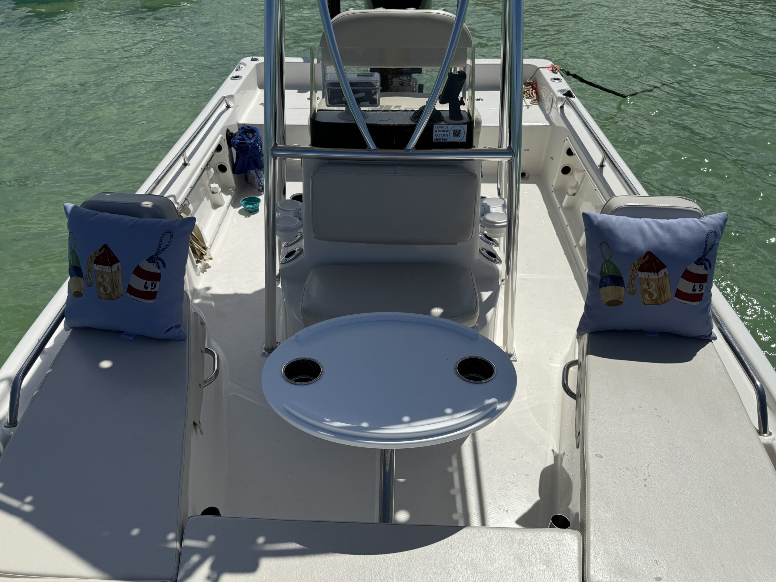 Interior of a center console boat with buoy-themed decorative pillows and a round table