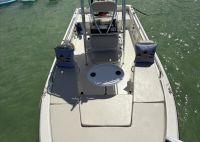 Top-down view of a small boat anchored in shallow water with floats and an umbrella in the background