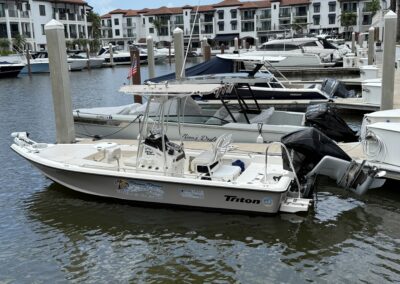 Center console boat named Piano Piano docked in a marina with Naples Bay Resort in the background