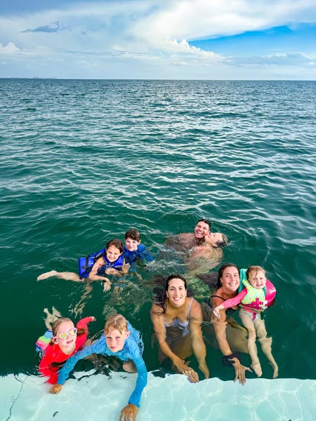 A joyful group floats in clear blue water beneath a wide open sky during a LivBlue charter aboard BRADventures near Keewaydin Island.