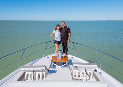Captain Bill and Stew Samantha standing on the bow of one of Sunshine's yacht with ocean backdrop