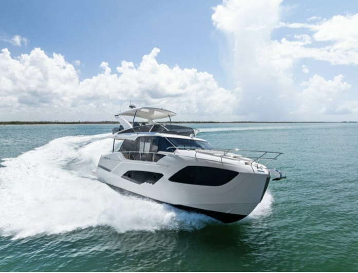 Side view of Piano Piano, a 22-foot center console bay boat, floating near a sandy beach in Naples, Florida, on calm, clear Gulf waters with no one onboard.